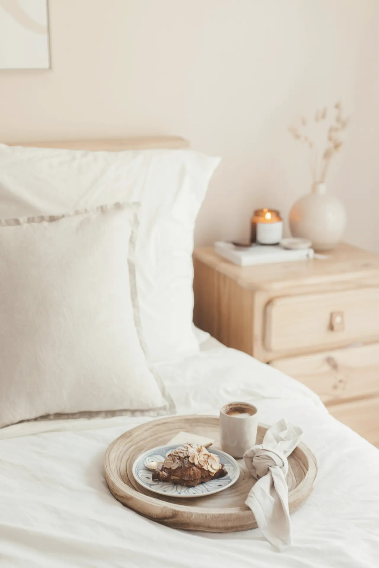 A bedside table with a small tray beside a freshly made bed