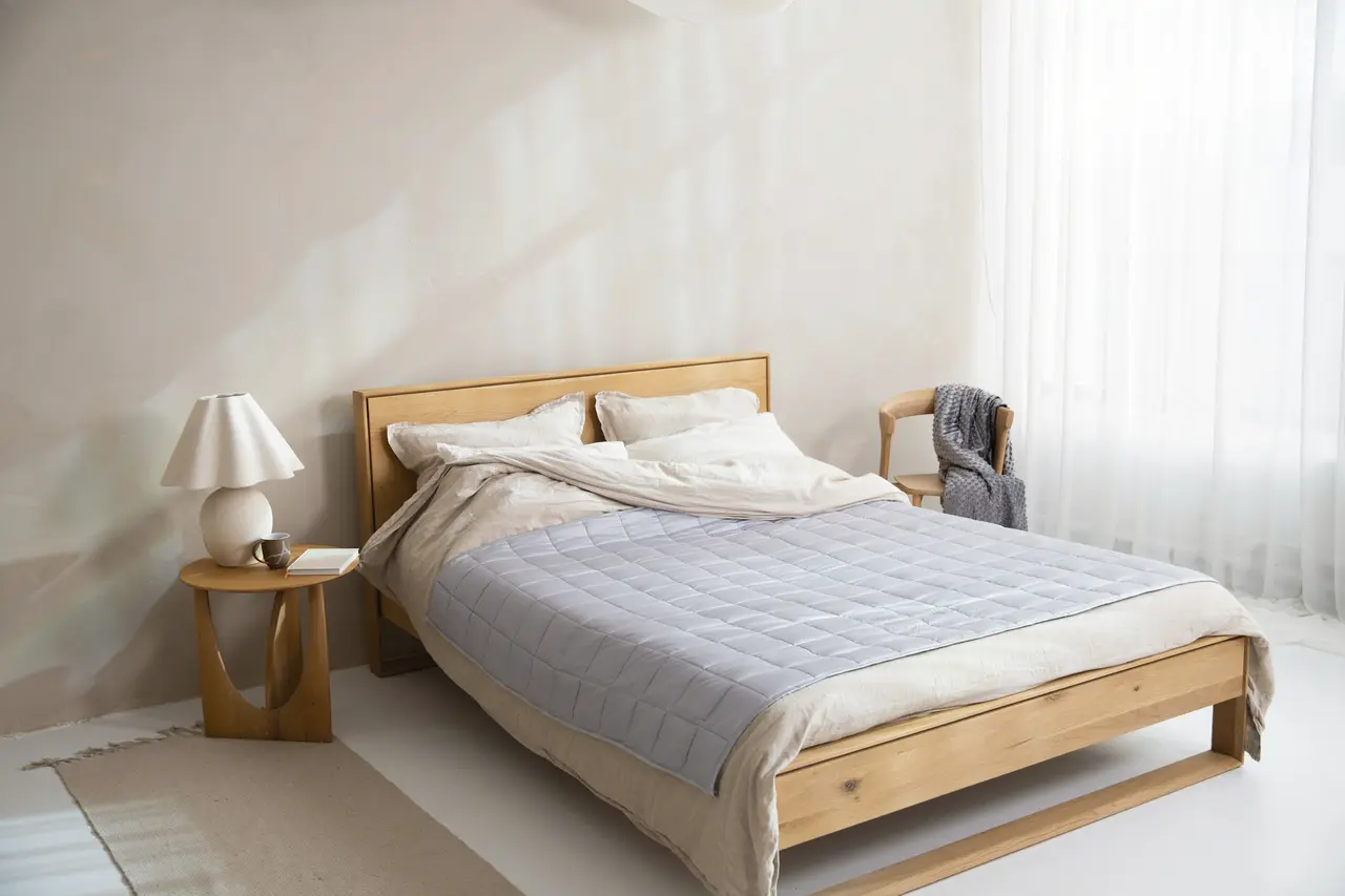 A bright bedroom with a freshly made timber bed and soft morning light