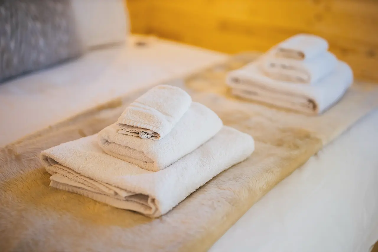 Folded white towels set out on a made bed