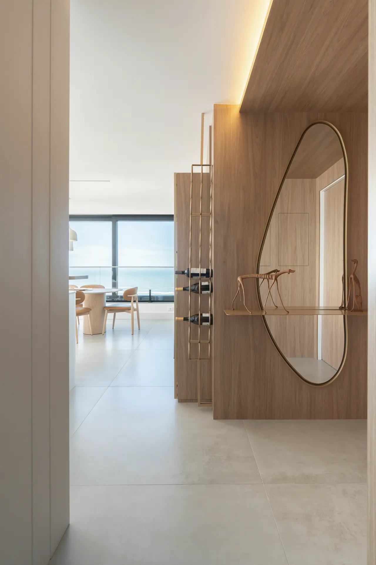 A modern apartment entrance with timber panelling and an oval mirror