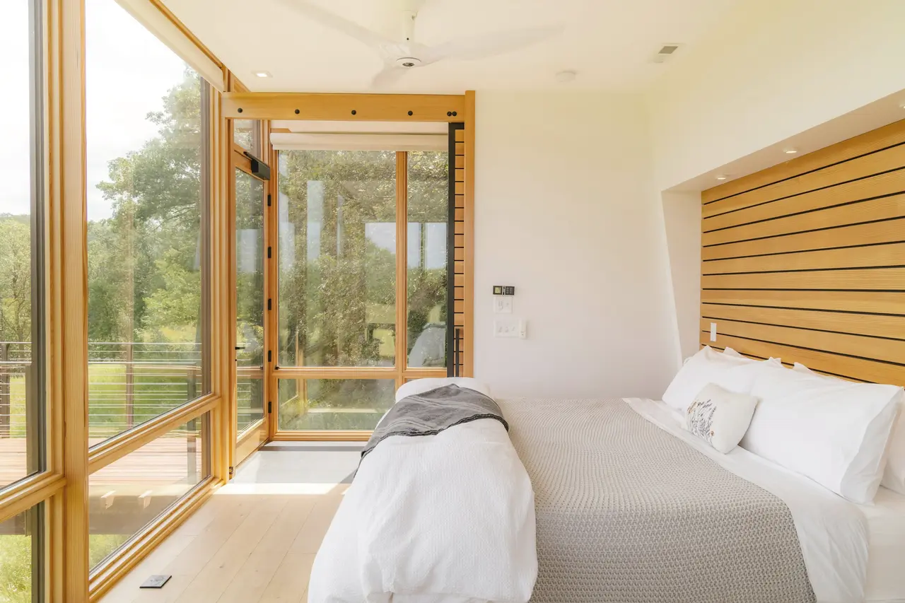 A holiday-home bedroom with timber walls and floor-to-ceiling glass