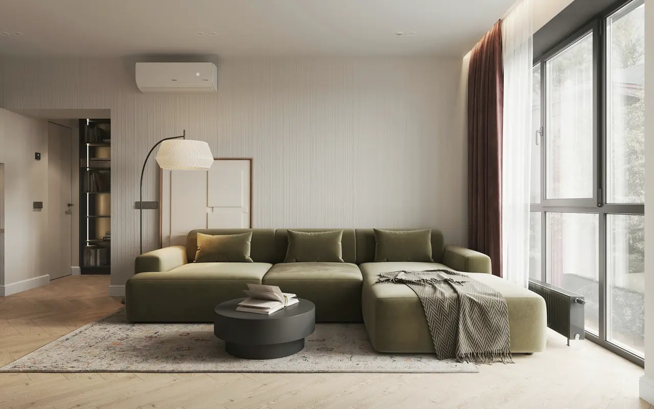 A living room with a sage-green sofa and large windows