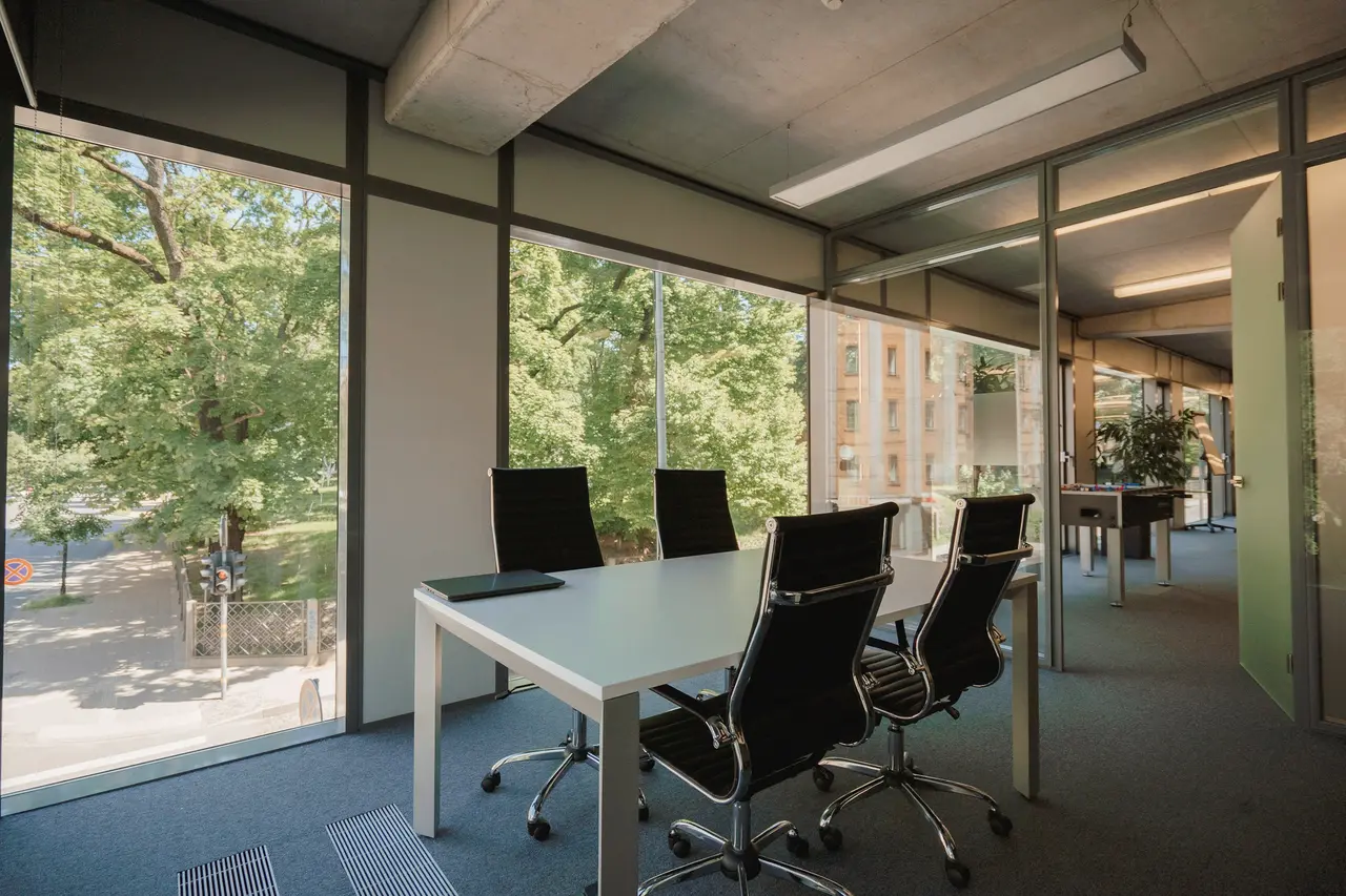 An office meeting room with a long table beside floor-to-ceiling windows