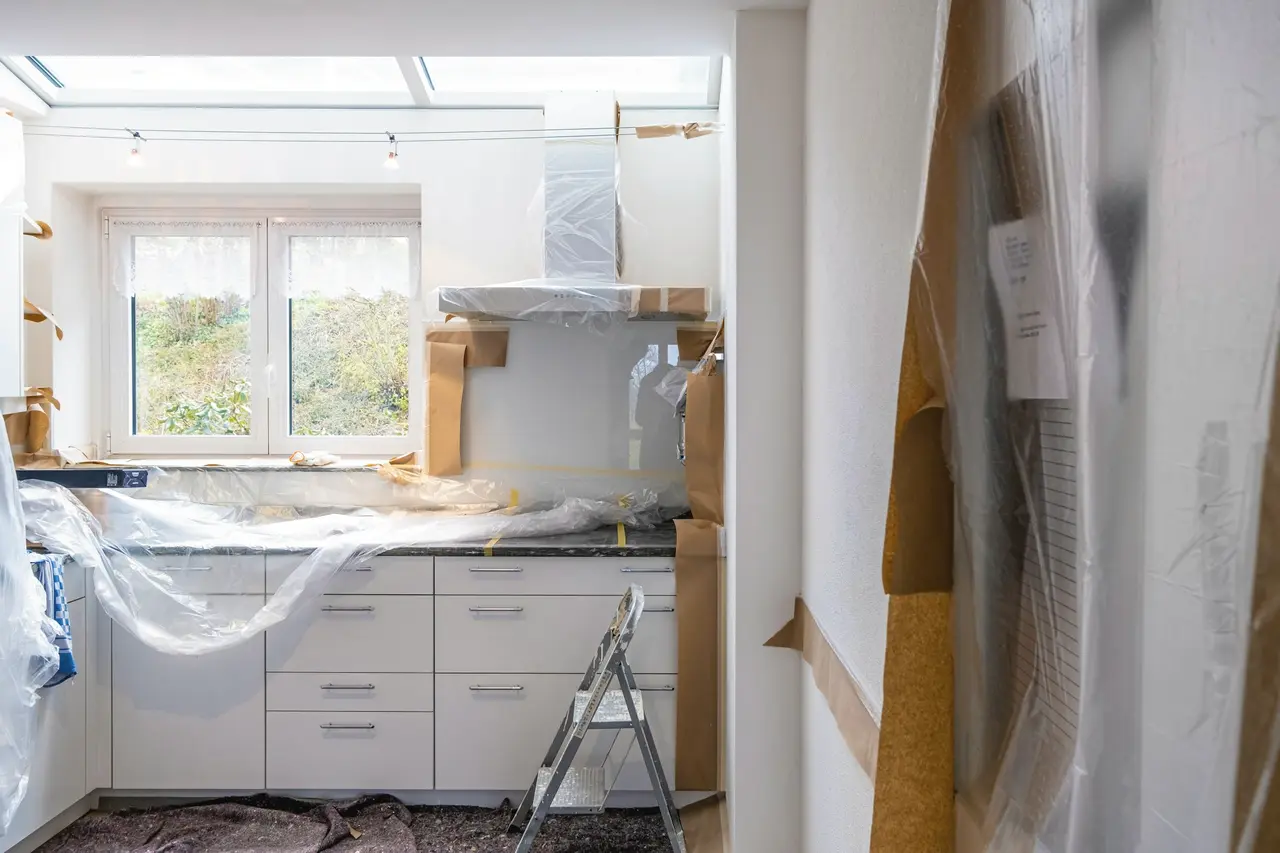 A kitchen mid-renovation with benches covered in protective plastic