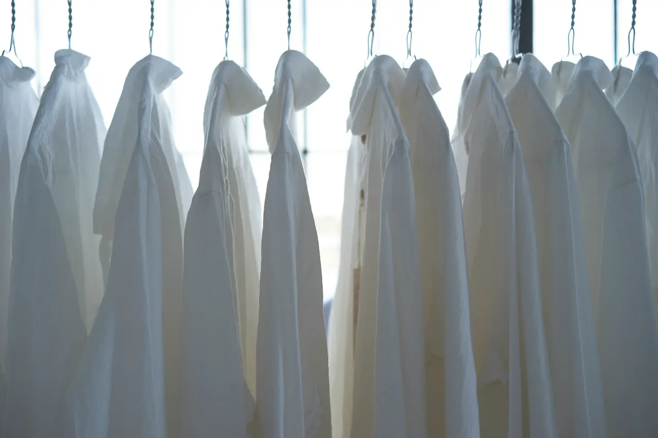 Pressed white shirts hanging in soft window light