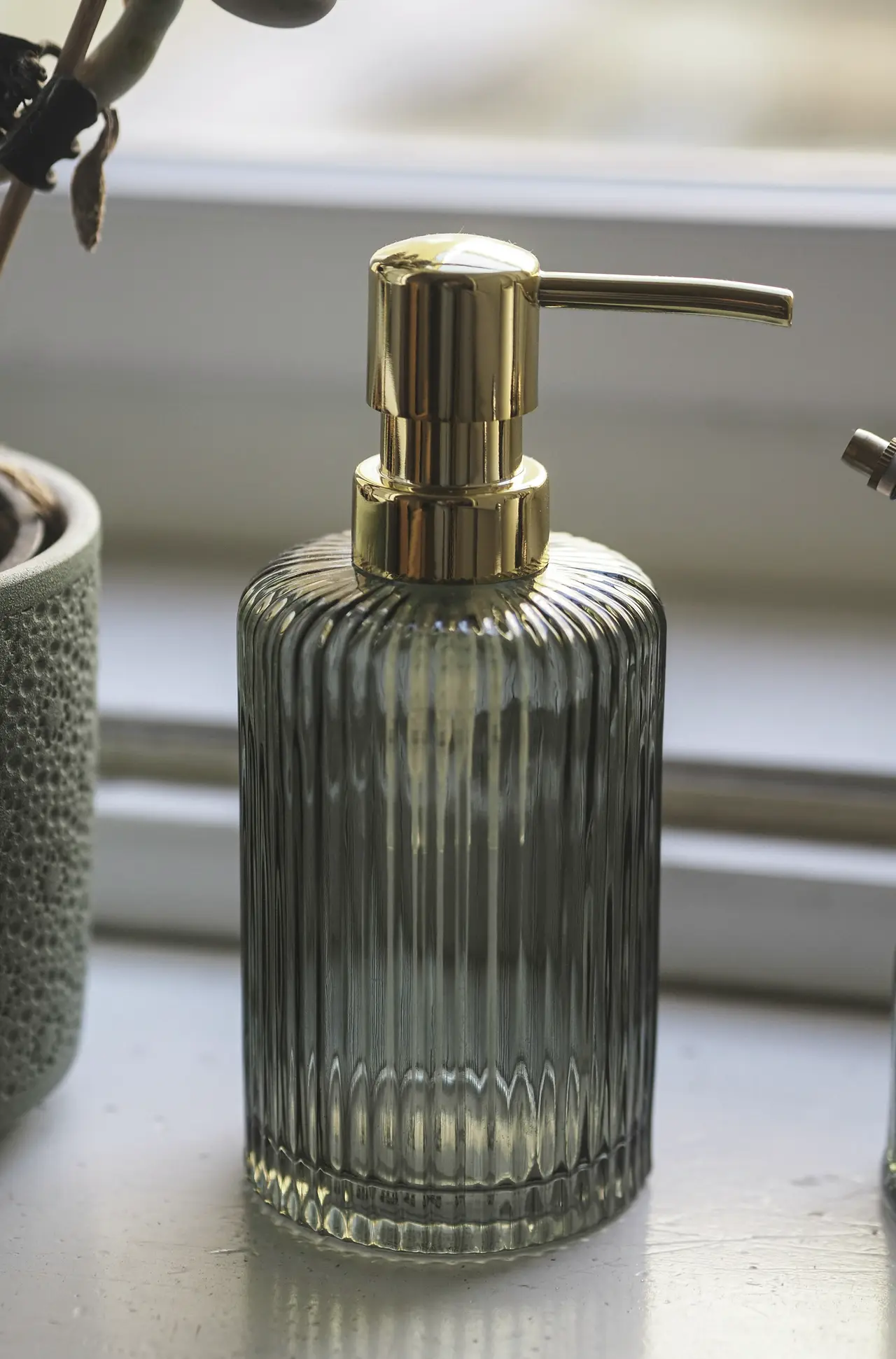 A glass soap dispenser on a clean bathroom benchtop