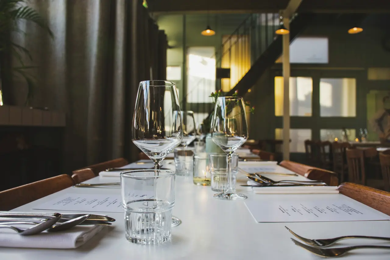 A long dining table set with glasses and napkins