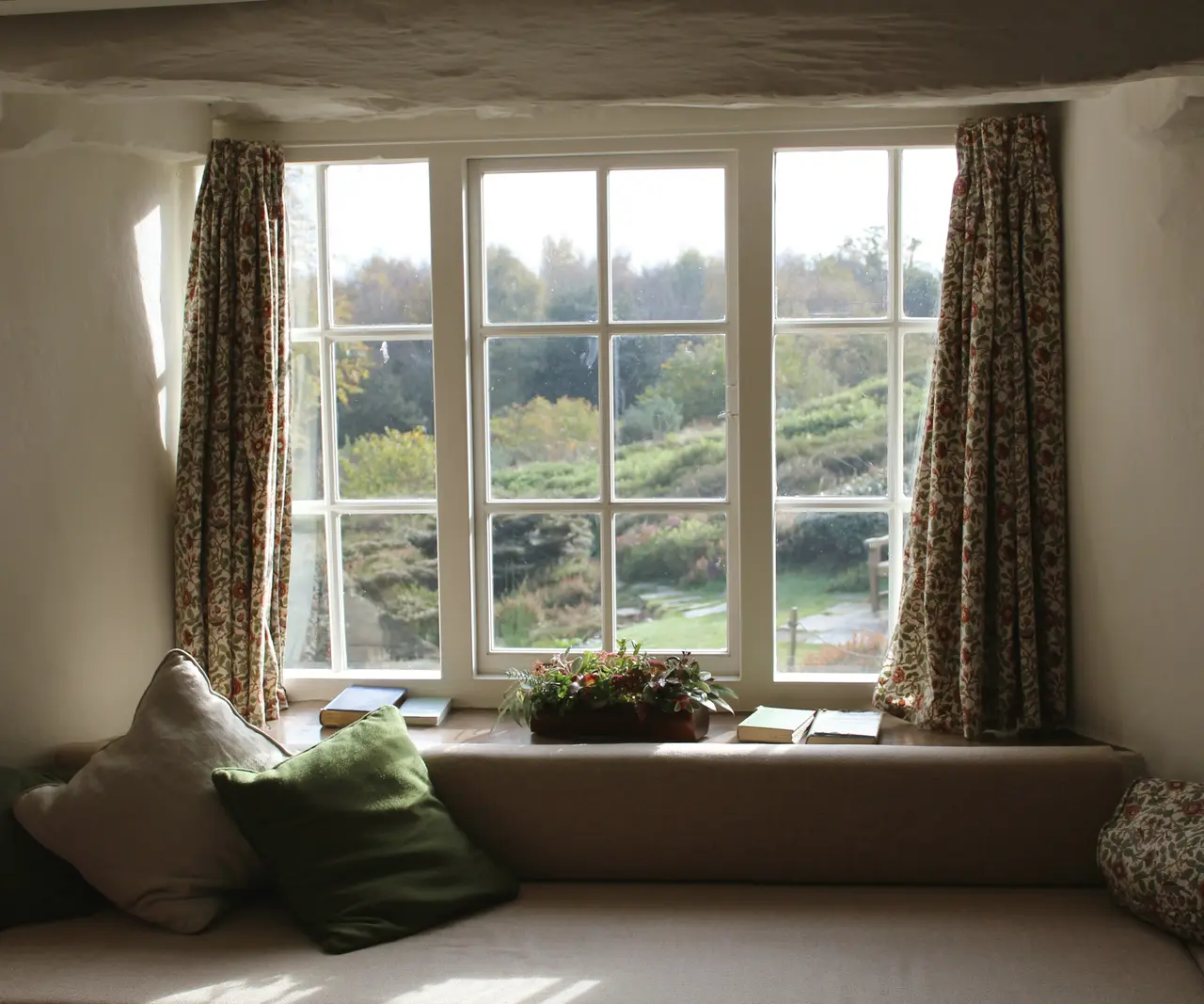 A window seat with cushions looking out over green hills